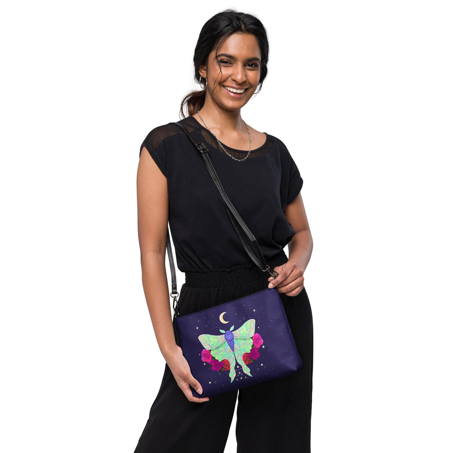 A woman wearing a black top and black pants models a purple crossbody bag featuring a colorful butterfly and crescent moon design, set against a plain white background.
