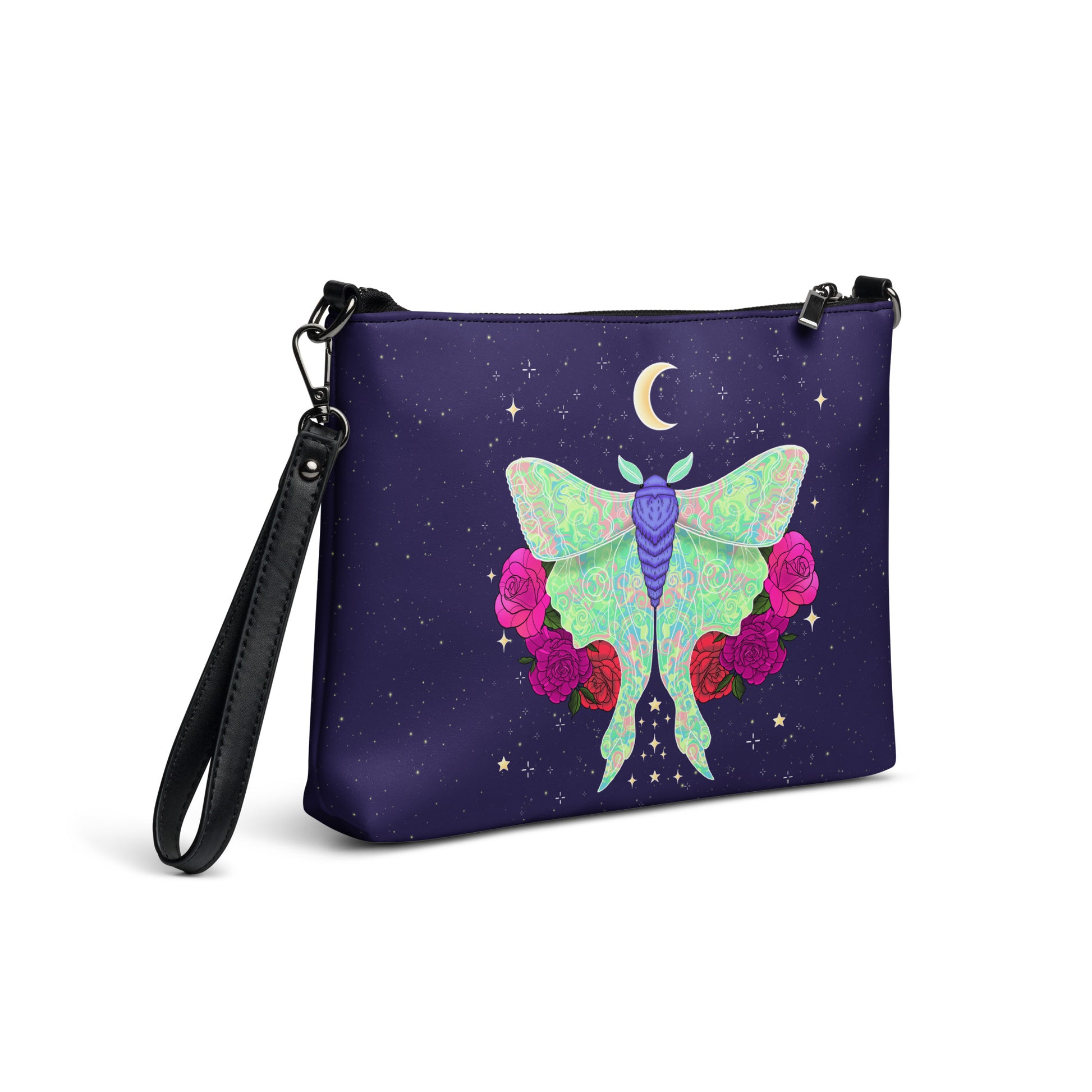 A wristlet clutch bag with a black strap, featuring a dark purple background printed with a large pastel green and purple moth, pink and red roses, and a small gold crescent moon surrounded by stars.