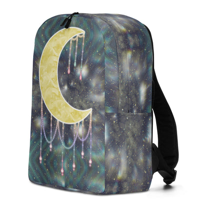 A backpack featuring a celestial print with a large gold crescent moon and dangling pearl-like chains over a dark blue and teal galaxy pattern, shown on a white background.